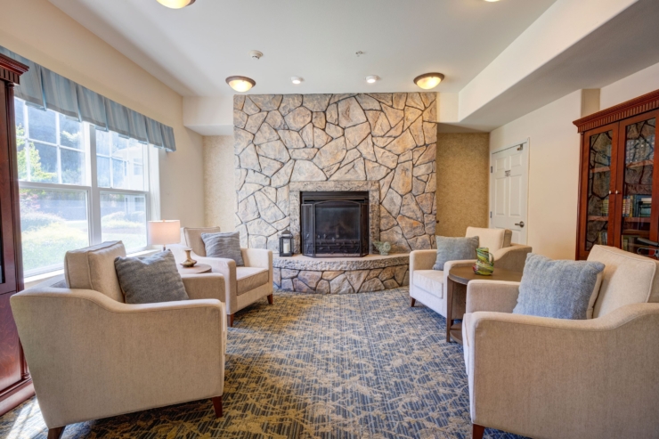 Cozy seating surrounds a warm fireplace, inviting residents to relax and connect in comfort.