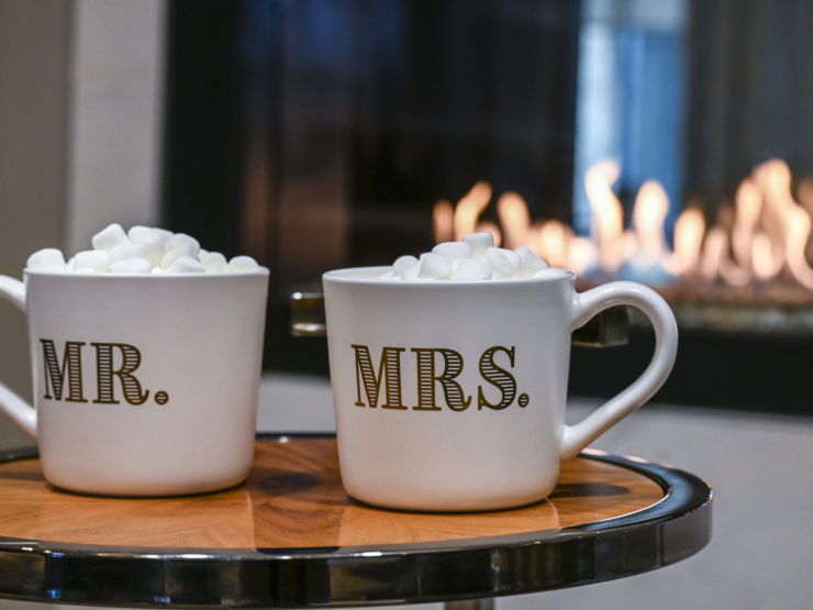 Warm mugs filled with marshmallows sit by a cozy fireplace, inviting moments of togetherness.