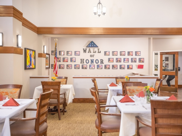 A welcoming dining area featuring a Wall of Honor, vibrant decor, and elegant table settings.