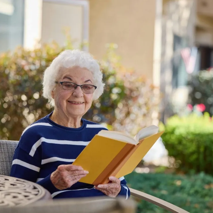 A resident enjoys a book outdoors, surrounded by vibrant greenery, embodying warmth and community.