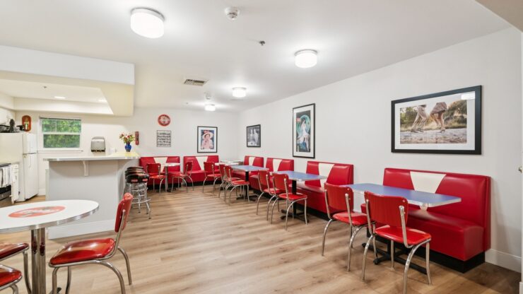 A welcoming dining area featuring vibrant red chairs and a friendly atmosphere, perfect for community gatherings.