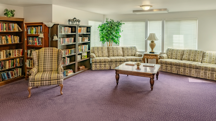 A cozy library lounge with inviting seating, warm lighting, and shelves filled with books, fostering community.