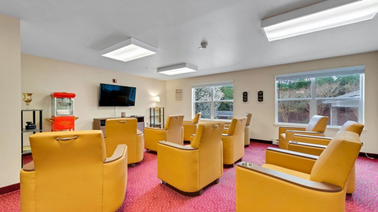 A cozy gathering space with warm yellow chairs, inviting natural light, and a popcorn machine, fostering community.