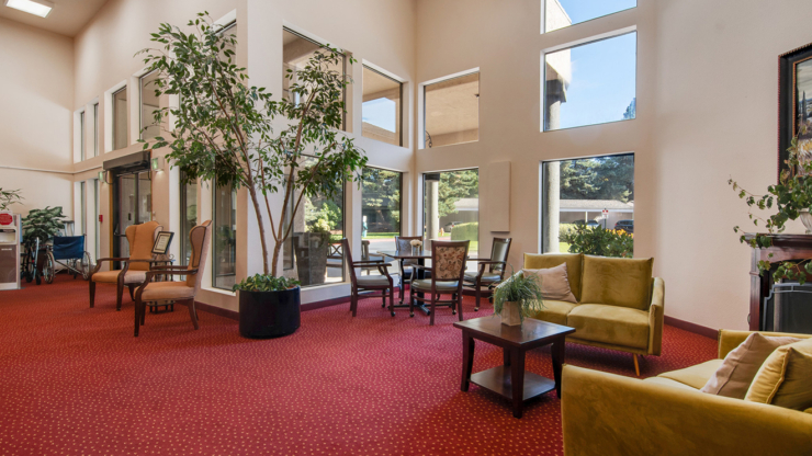 Bright, inviting lounge with comfortable seating, greenery, and a warm atmosphere for community gatherings.