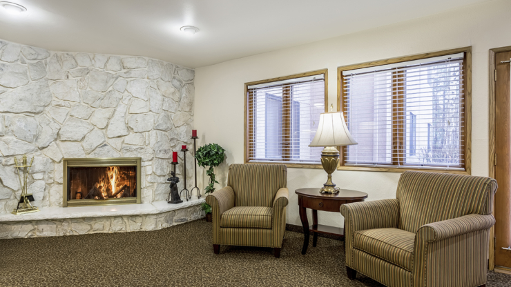 A welcoming lounge with a warm fireplace, inviting armchairs, and soft lighting, perfect for gatherings.
