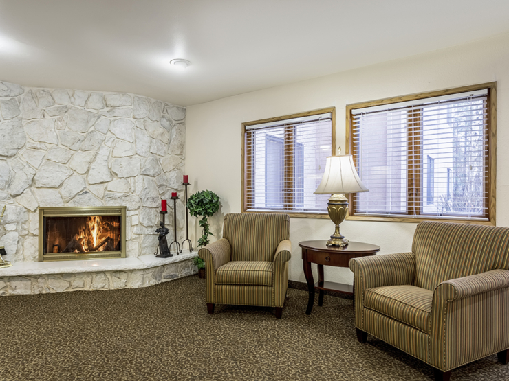 A cozy, inviting lounge with comfortable chairs, a warm fireplace, and soft lighting, perfect for relaxation.