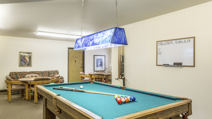 A vibrant activity room fosters community engagement, featuring a pool table and cozy seating.
