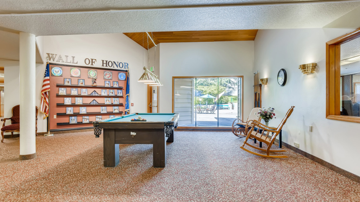 A welcoming lounge featuring a pool table, cozy seating, and a tribute wall, perfect for community gatherings.