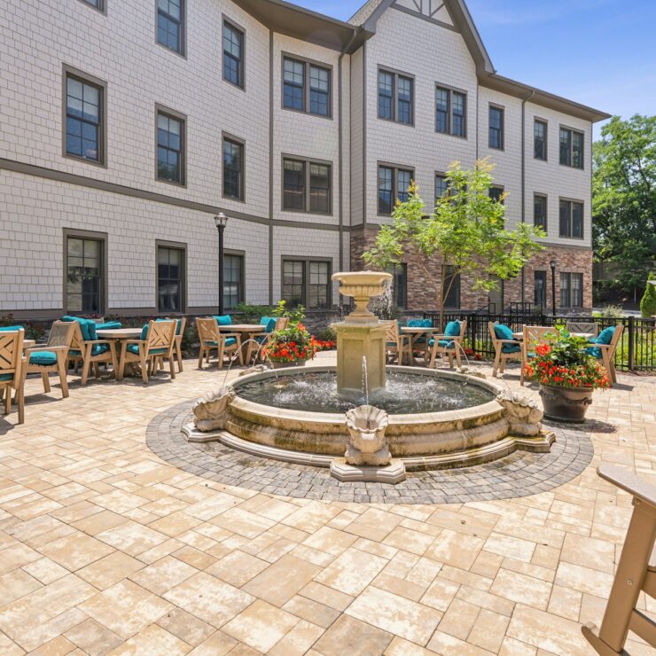 A serene courtyard featuring a charming fountain, surrounded by inviting seating and greenery.