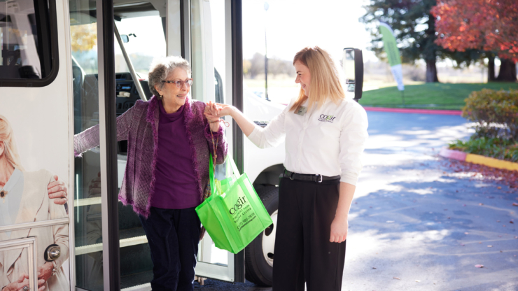 A warm welcome as a resident steps off the bus, embraced by friendly support and autumn's vibrant colors.