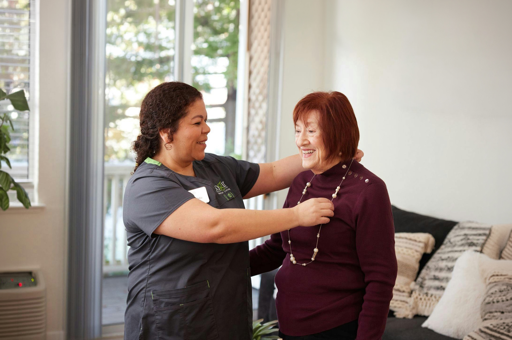 A warm interaction between a caregiver and resident highlights community spirit and joyful moments.