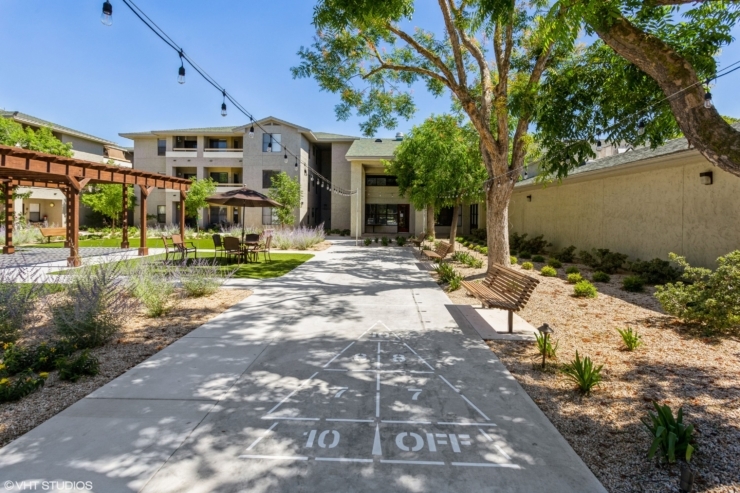 A welcoming outdoor space features shaded seating, vibrant gardens, and pathways for leisurely strolls.