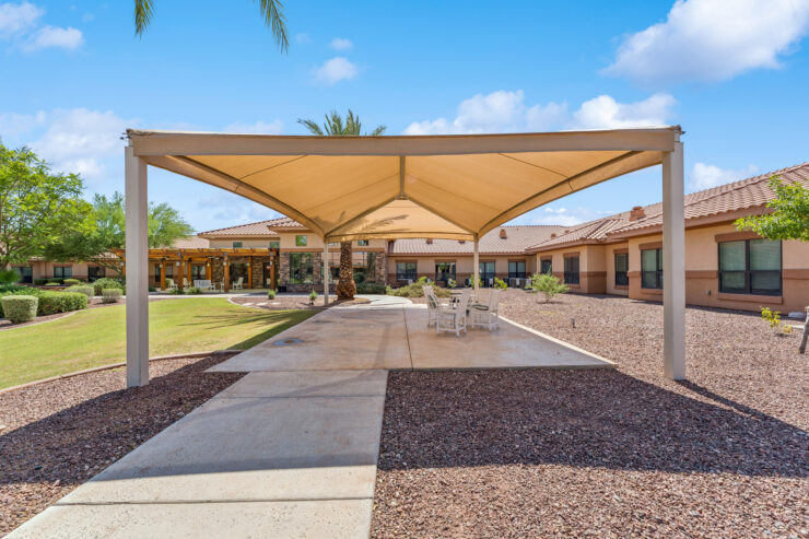 A welcoming outdoor space with shaded seating, inviting residents to enjoy the sunny atmosphere together.