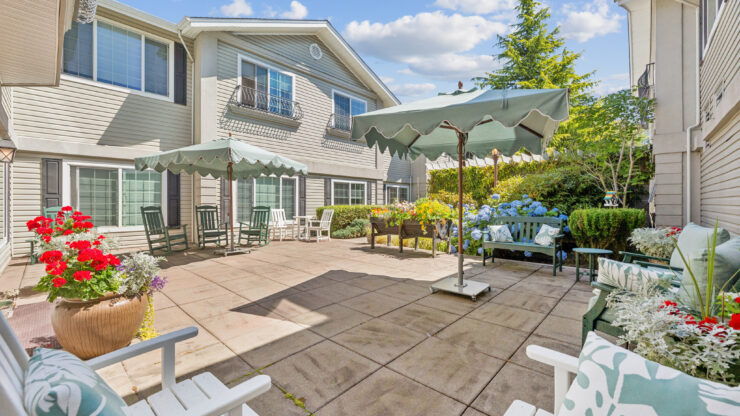 A welcoming outdoor space with shaded seating, vibrant flowers, and a serene atmosphere for relaxation.