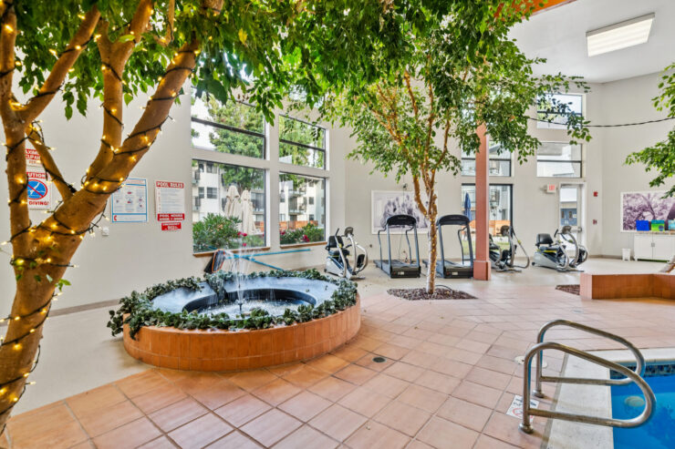 A bright, inviting space featuring lush greenery and a soothing water fountain, perfect for relaxation and community.