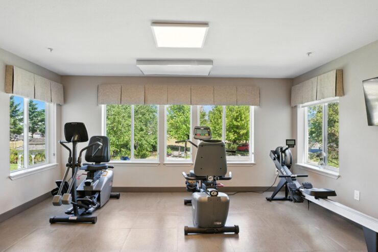 A bright fitness area with modern equipment and large windows, inviting a sense of community and wellness.