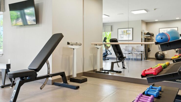 A bright, inviting fitness area featuring modern equipment, colorful weights, and comfortable seating.