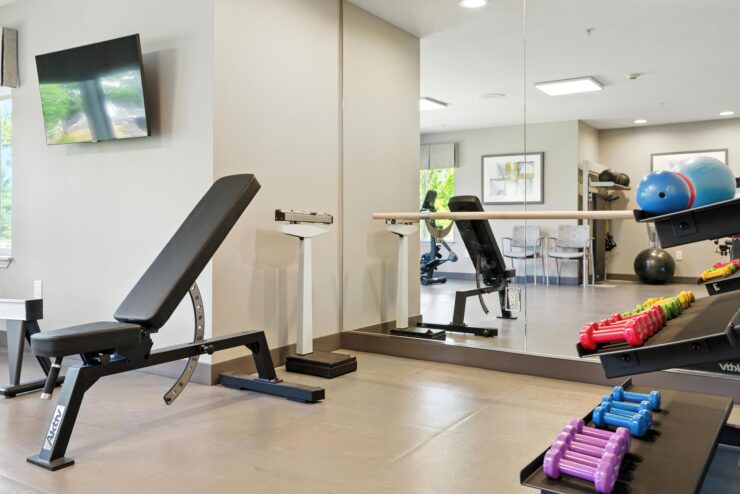 A bright, inviting fitness area featuring modern equipment, colorful weights, and comfortable seating.
