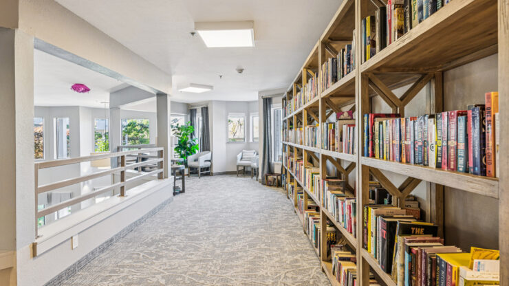 A welcoming hallway lined with bookshelves, inviting residents to relax and connect in a vibrant community.