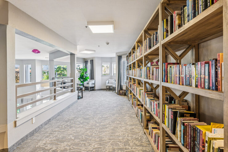 A welcoming hallway lined with bookshelves, inviting residents to relax and connect in a vibrant community.