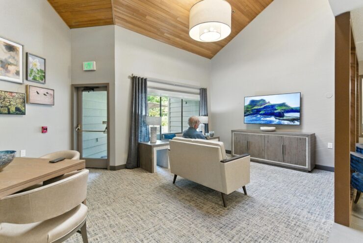A welcoming lounge with warm lighting, inviting seating, and a resident enjoying a moment of relaxation.
