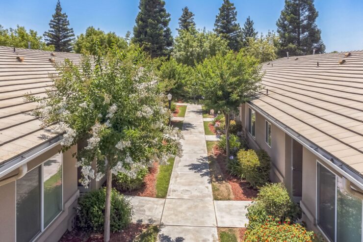 A serene pathway lined with trees and vibrant gardens invites community and connection.
