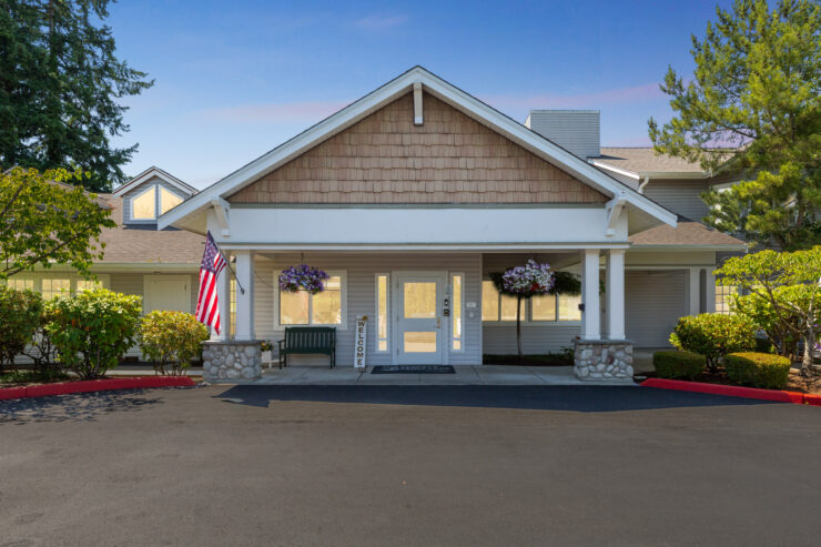 A welcoming entrance with vibrant flowers and an American flag, inviting community and comfort.