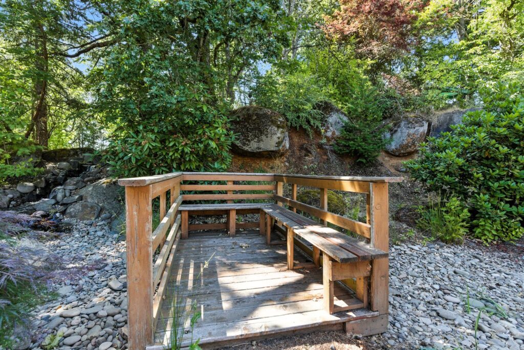 A serene outdoor seating area surrounded by lush greenery, perfect for relaxation and community gatherings.