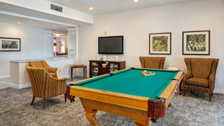 A welcoming game room featuring a billiard table, comfortable seating, and a vibrant atmosphere for socializing.