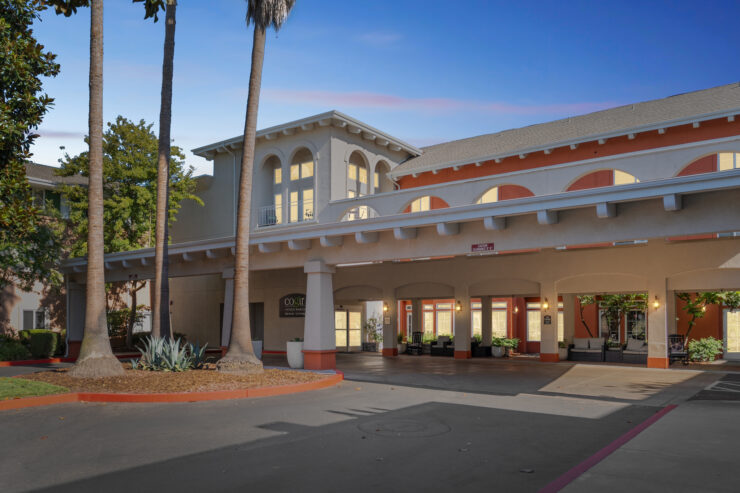 A welcoming entrance surrounded by palm trees, inviting residents to a vibrant community.