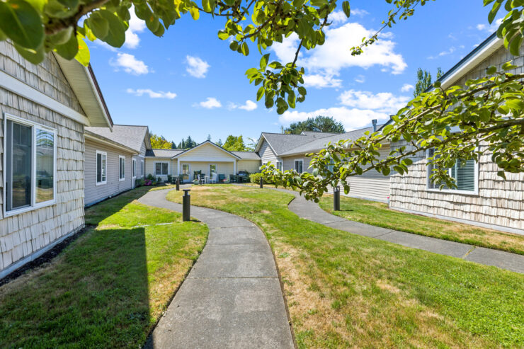 A welcoming community space with winding paths, lush greenery, and bright blue skies invites connection.