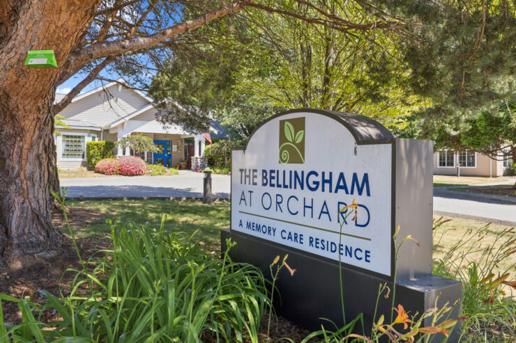 Welcoming sign at The Bellingham at Orchard, surrounded by lush greenery and a vibrant, friendly atmosphere.