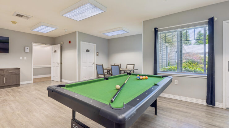 A welcoming game room featuring a pool table and comfortable seating, perfect for community gatherings.