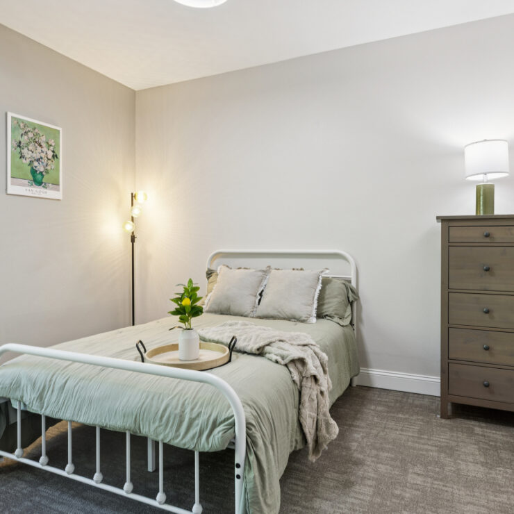 A welcoming bedroom featuring soft decor, inviting warmth, and a sense of community and comfort.
