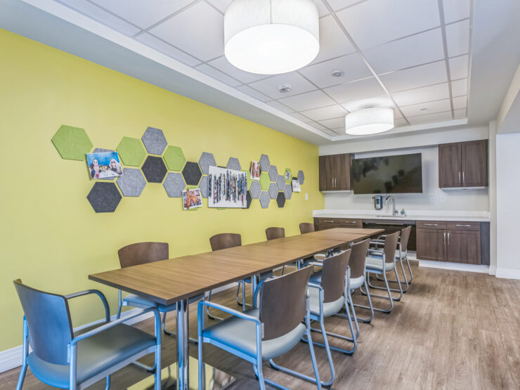 A welcoming communal space featuring a vibrant yellow wall, modern furnishings, and engaging decor.