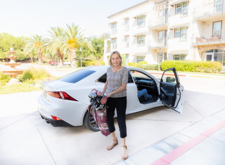 A welcoming resident steps out of her car, ready for a day of fun in a vibrant, sunny community.
