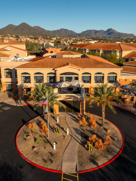 A welcoming entrance surrounded by vibrant landscaping and scenic mountains, inviting community and comfort.