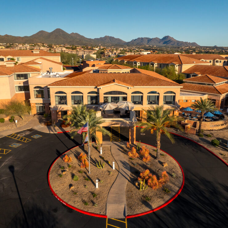 A welcoming entrance surrounded by vibrant landscaping and scenic mountains, inviting community and comfort.