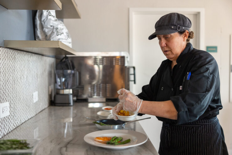 A dedicated chef prepares vibrant dishes, showcasing care and community in a welcoming kitchen.