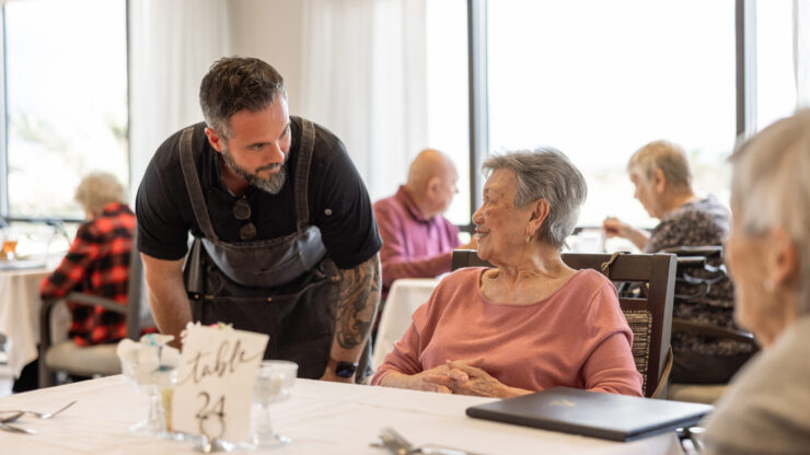 A warm dining atmosphere where friendly staff engage with residents, fostering community and joy.