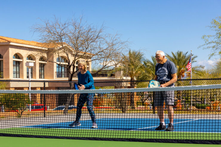 Active residents enjoy a friendly game of pickleball under clear skies, fostering community and joy.