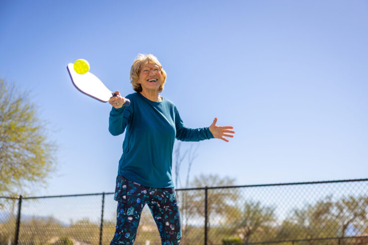 An active resident enjoys a game outdoors, radiating joy and community spirit under a clear blue sky.