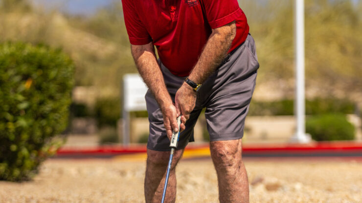 A resident enjoys a sunny day on the putting green, fostering camaraderie and active living.