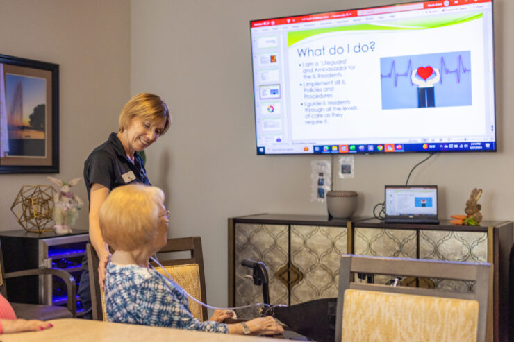A warm interaction unfolds as a staff member attentively assists a resident, fostering community and care.