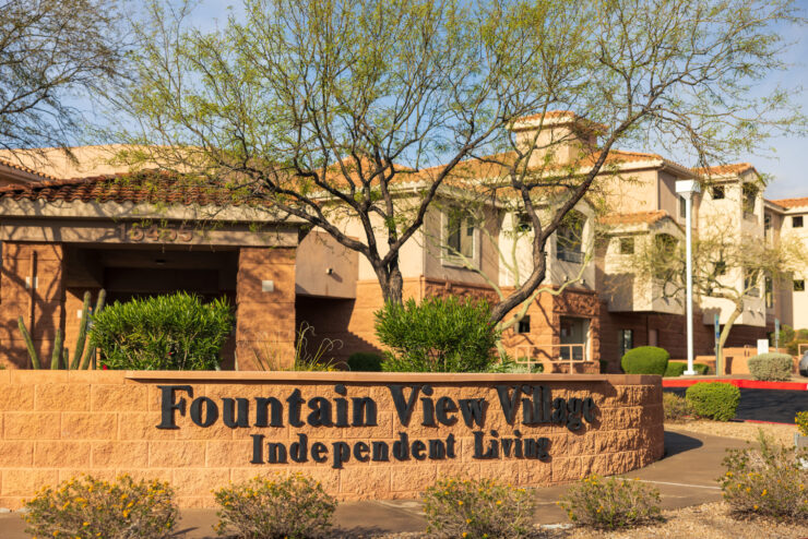 Welcoming community entrance with vibrant greenery, reflecting a warm, inviting atmosphere for residents.