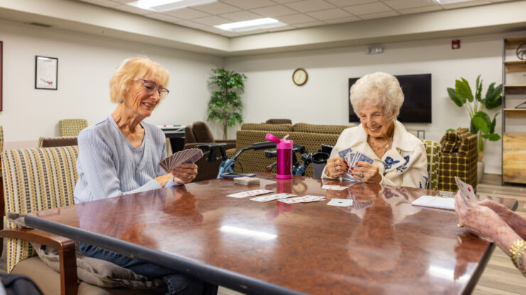 Engaging smiles and friendly card games create a warm, inviting atmosphere among residents.