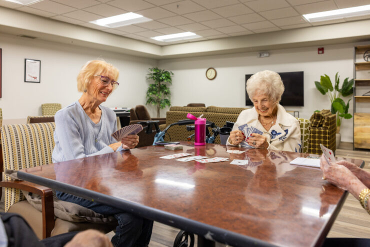 Engaging smiles and friendly card games create a warm, inviting atmosphere among residents.