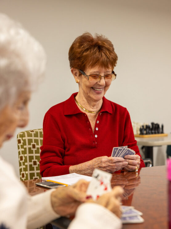 Engaging seniors enjoy a lively card game, sharing smiles and companionship in a warm atmosphere.