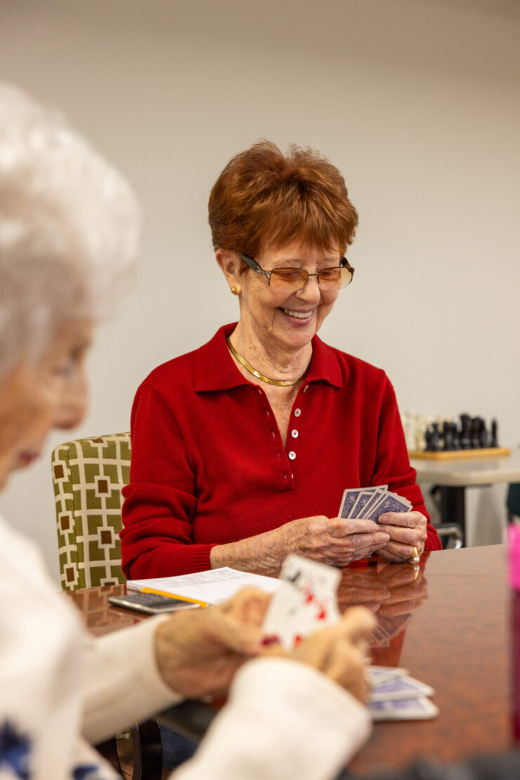 Engaging seniors enjoy a lively card game, sharing smiles and companionship in a warm atmosphere.