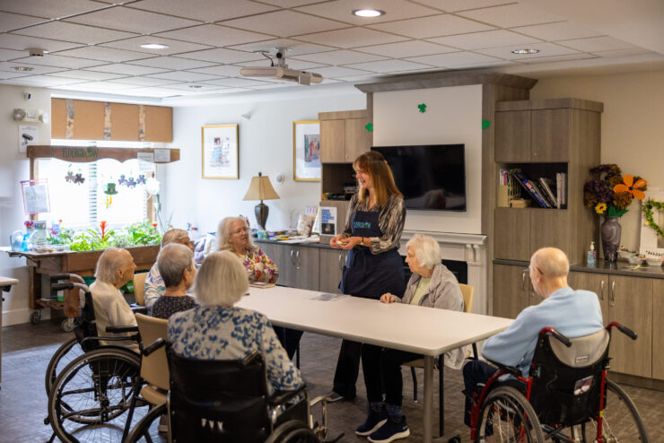 Engaging residents share smiles as a staff member leads a lively activity in a welcoming space.